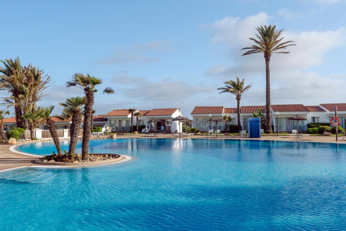 Una gran piscina con palmeras y casas. en AluaSun Mediterráneo, en S'Algar