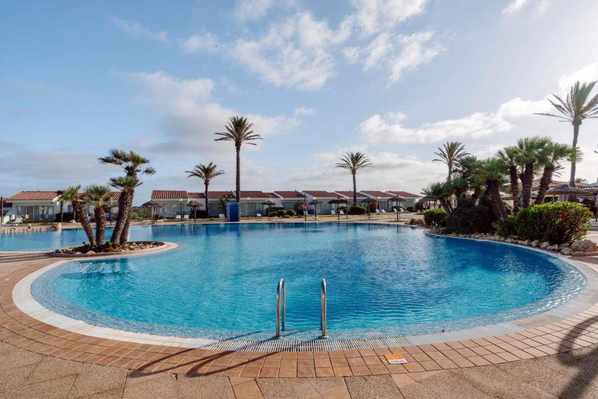 Una gran piscina con palmeras en un complejo turístico. en AluaSun Mediterráneo, en S'Algar
