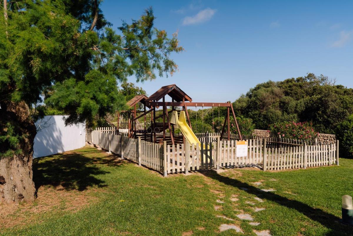 Un parque infantil detrás de una valla con un tobogán en AluaSun Mediterráneo, en S'Algar