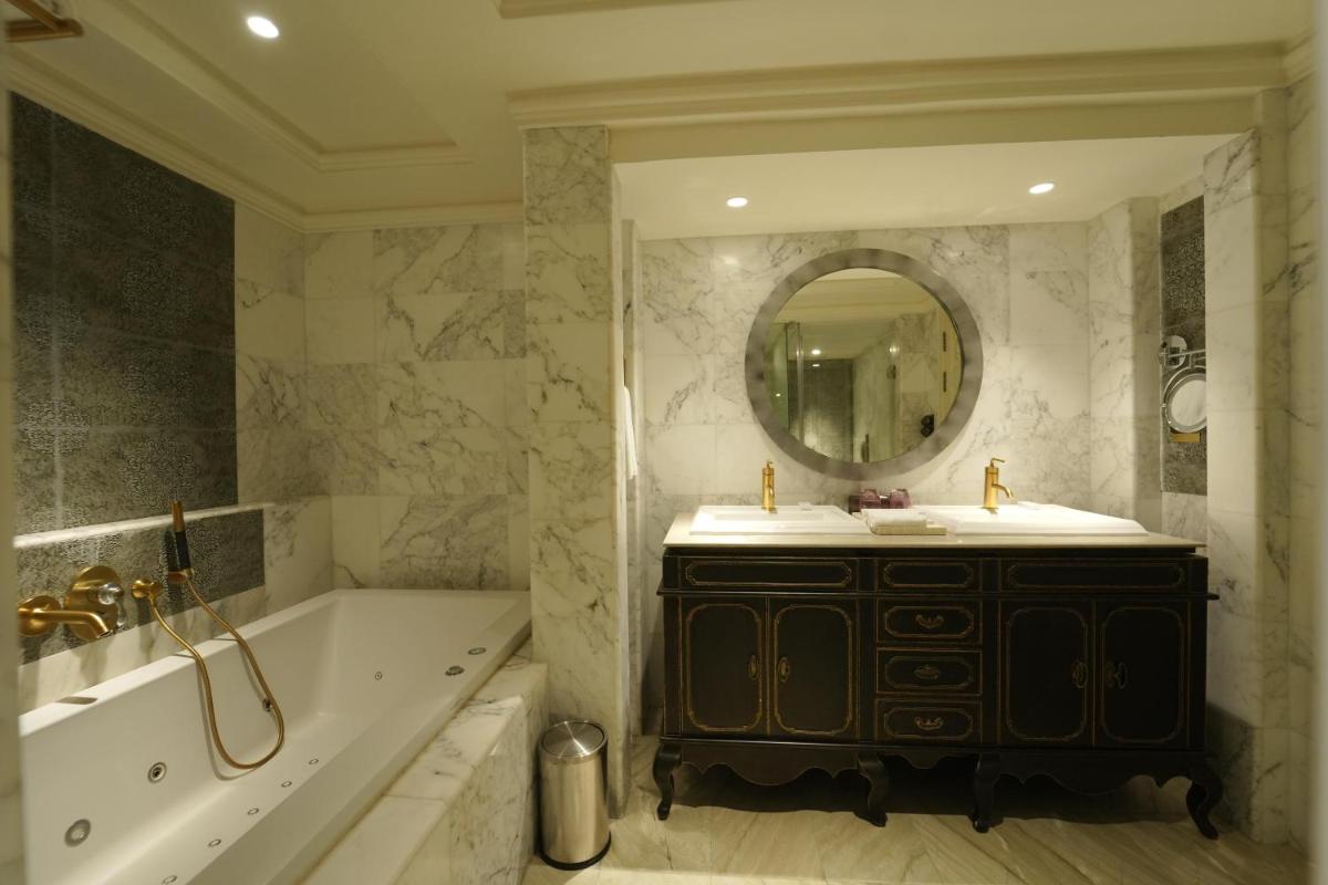 a bathroom with a tub and a sink and a mirror at Fragrant Nature Kochi - A Five star Classified Hotel in Cochin
