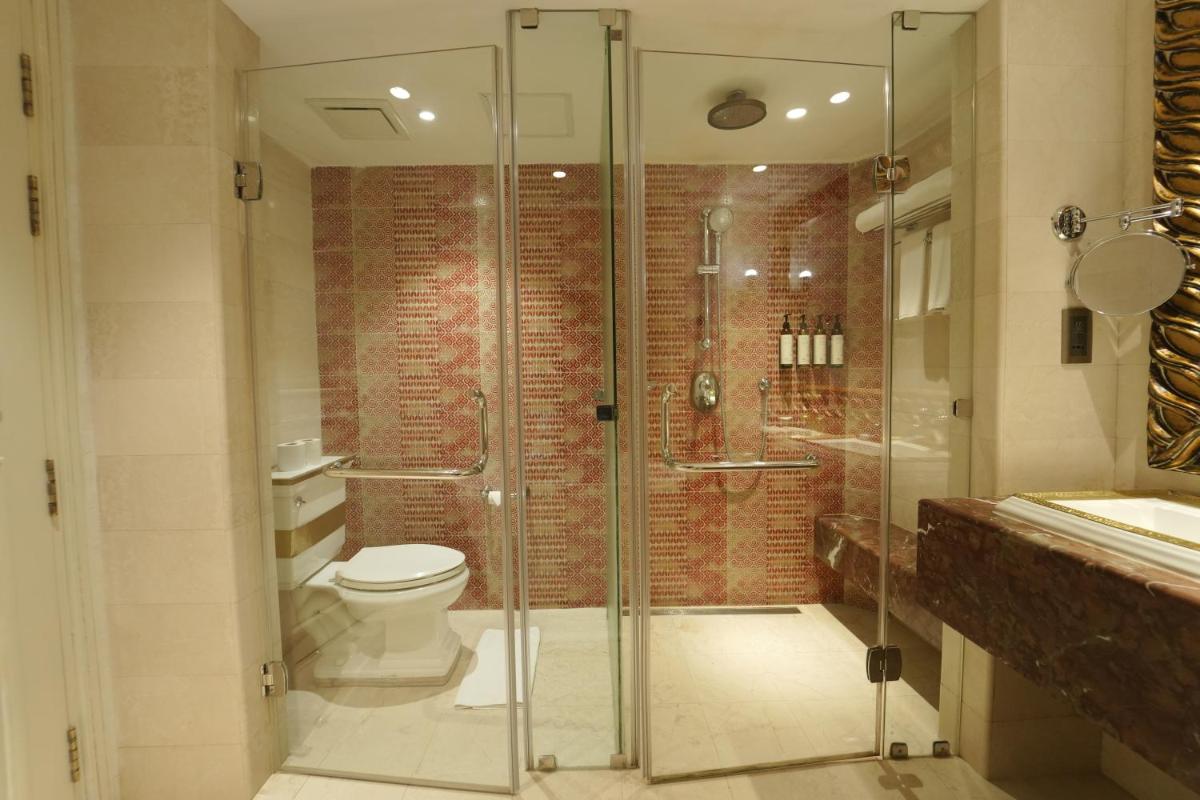 a bathroom with a toilet and a glass shower at Fragrant Nature Kochi - A Five star Classified Hotel in Cochin