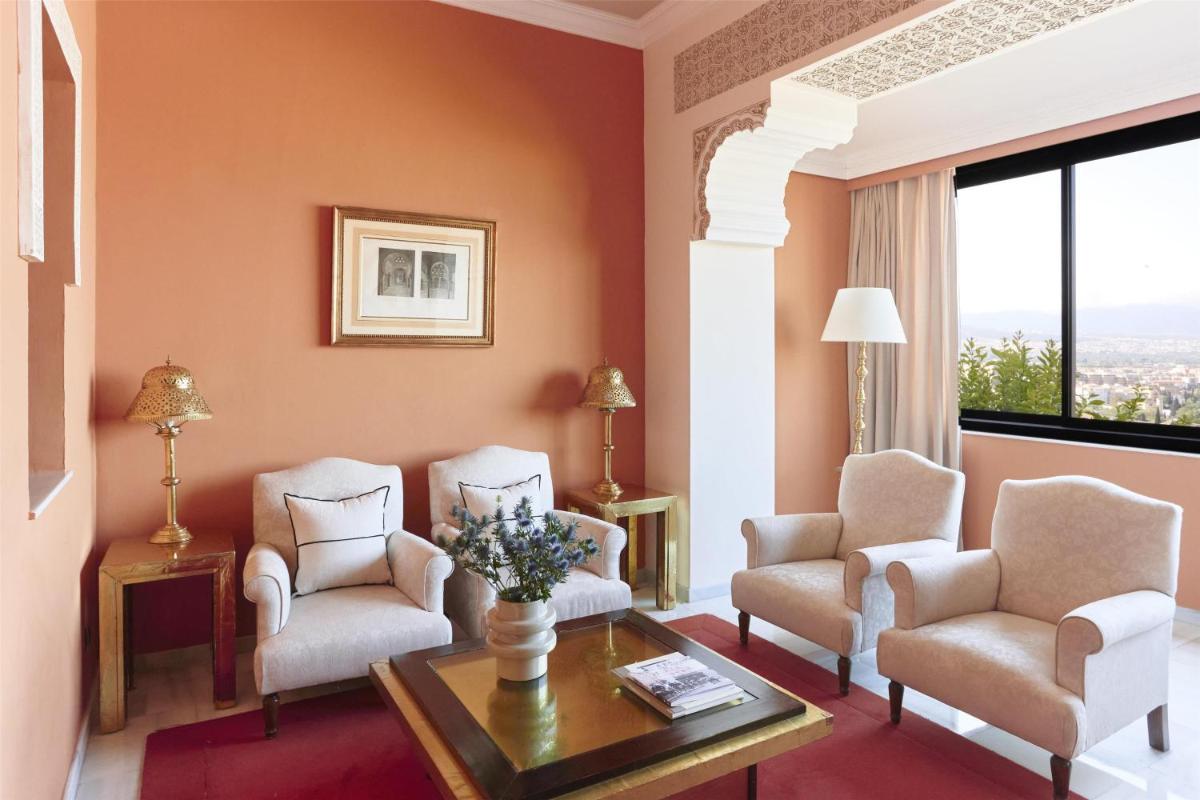Una sala de estar con dos sillas y una mesa. en Alhambra Palace Hotel, en Granada