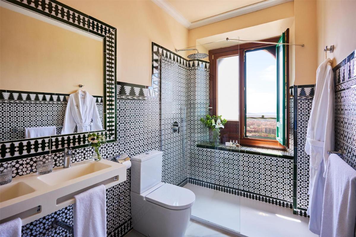 Un baño con inodoro, lavabo y espejo. en Alhambra Palace Hotel, en Granada