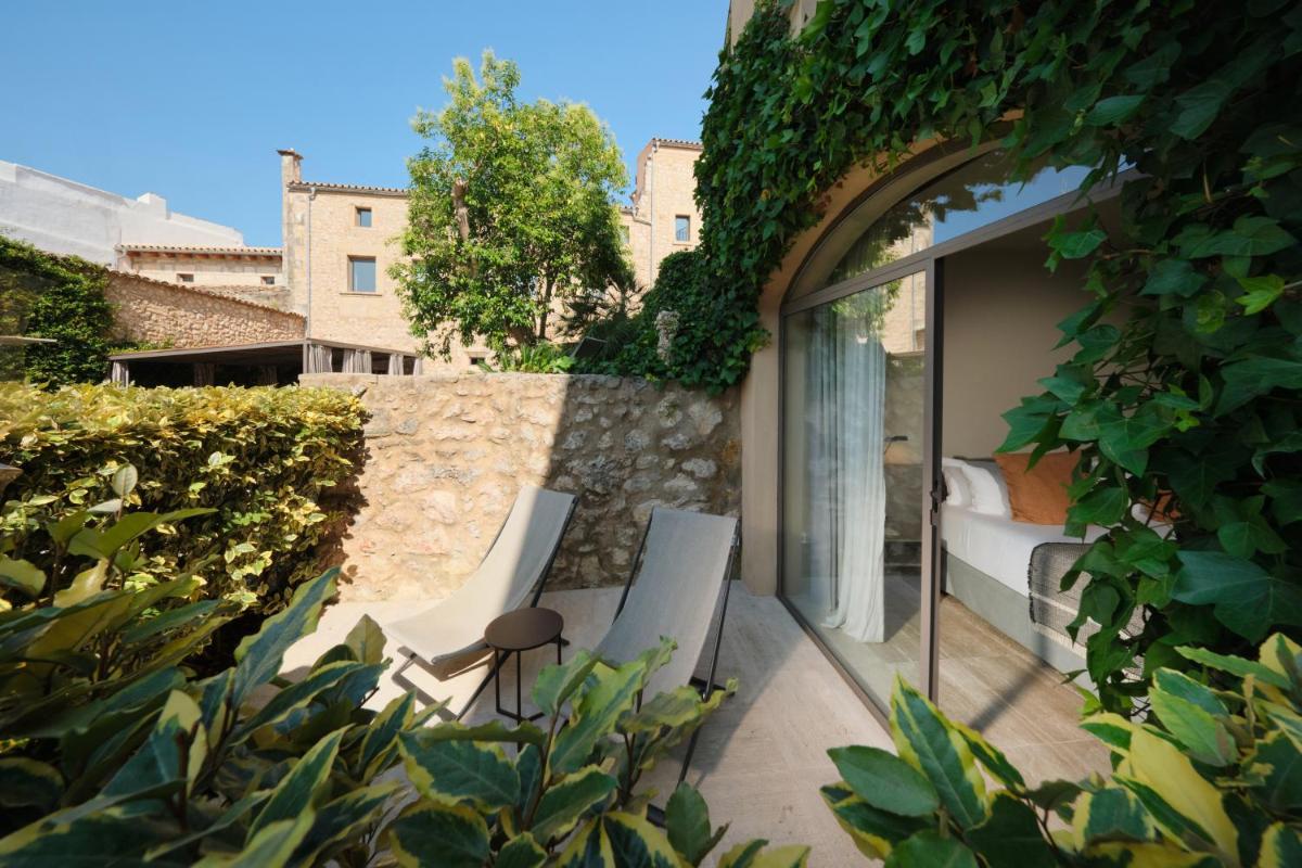 un patio con 2 sillas y una cama en un edificio en Can Aulí Luxury Retreat - Adults Only, en Pollensa