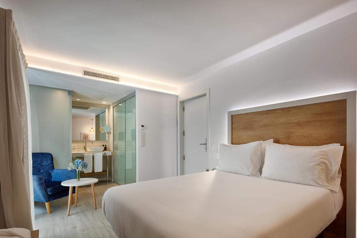 Un dormitorio con una gran cama blanca y una silla azul. en Eurostars Puerto de Ibiza, en Ibiza
