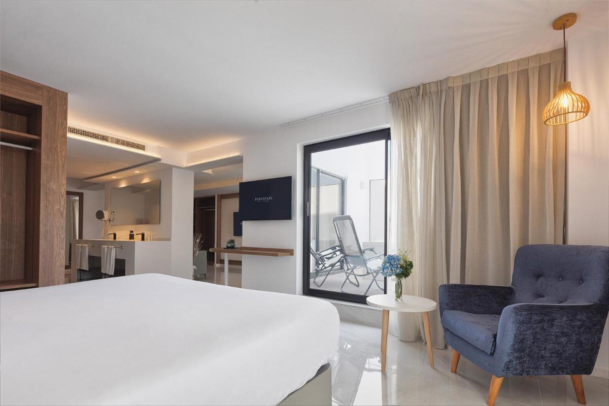 1 dormitorio con 1 cama blanca grande y 2 sillas en Eurostars Puerto de Ibiza, en Ibiza