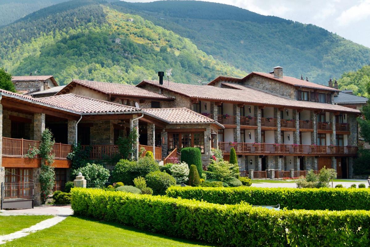 un gran edificio con jardín frente a una montaña en Hotel La Coma, en Setcases