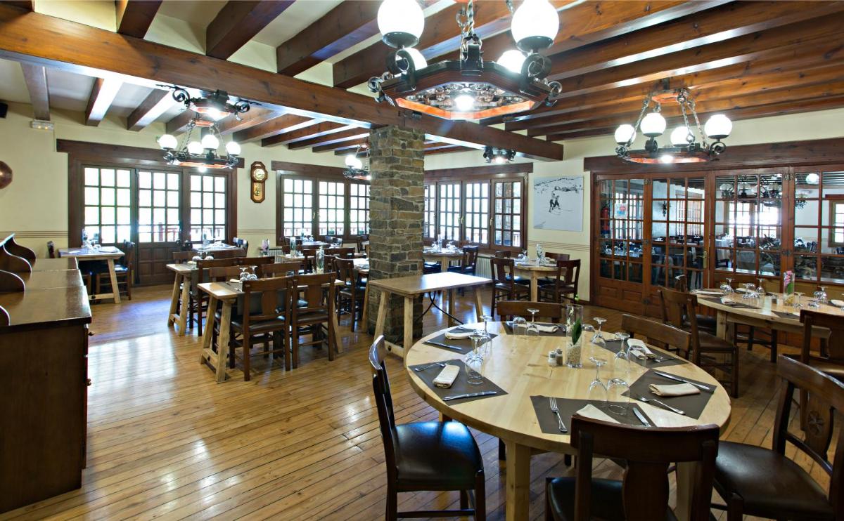 Un restaurante con suelos de madera, mesas y sillas. en Hotel La Coma, en Setcases