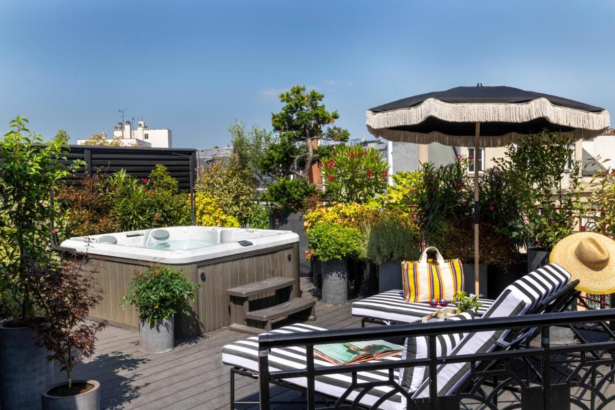 un bain à remous sur une terrasse avec une chaise et un parasol dans l'établissement Hôtel Félicien & Spa, à Paris