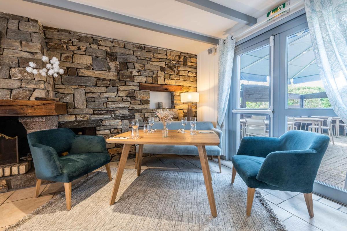 un salon avec une table et deux chaises et un mur en pierre dans l'établissement La Désirade - Hôtel, Spa & Restaurant, à Bangor