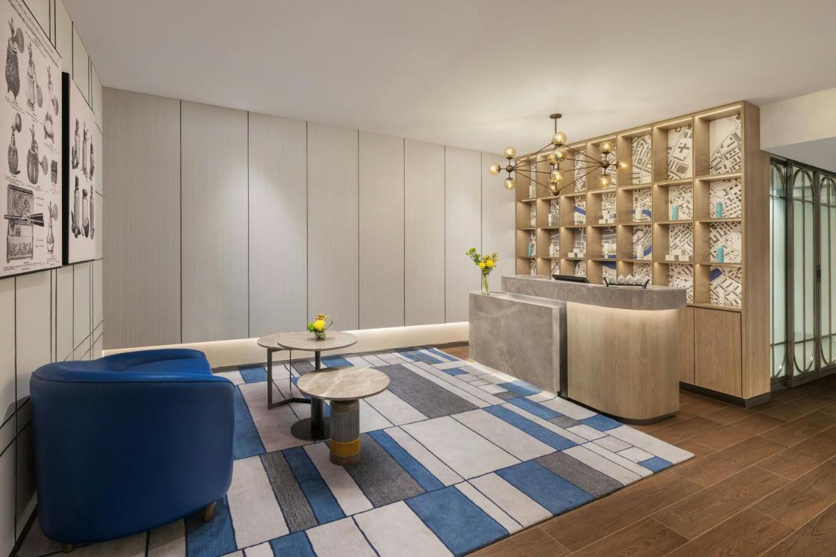 a lobby with a table and blue chairs and a counter at Le Meridien Ahmedabad in Ahmedabad