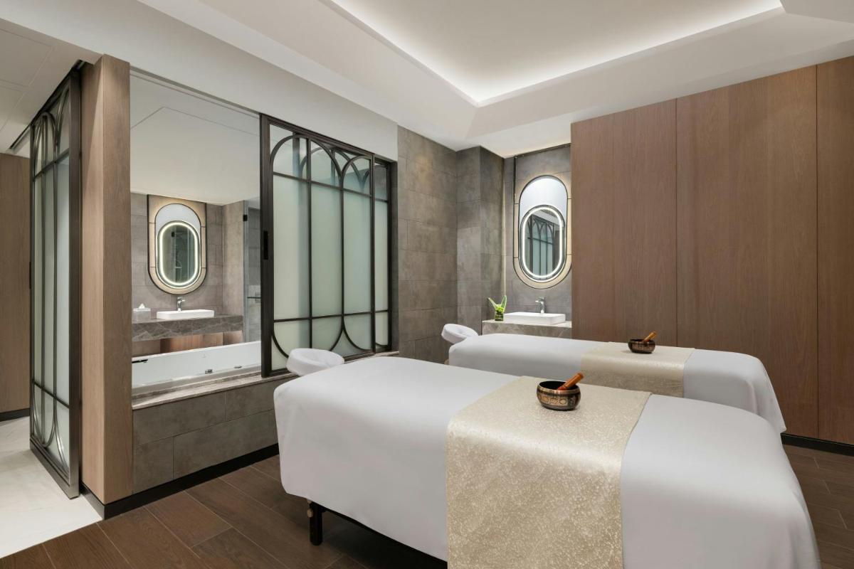 a bedroom with two beds and two sinks and mirrors at Le Meridien Ahmedabad in Ahmedabad