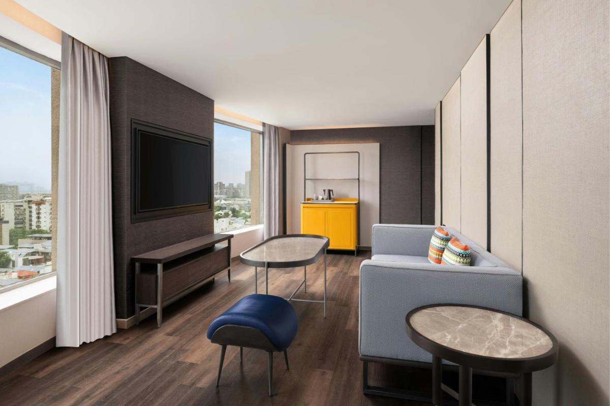 a living room with a couch and a tv at Le Meridien Ahmedabad in Ahmedabad