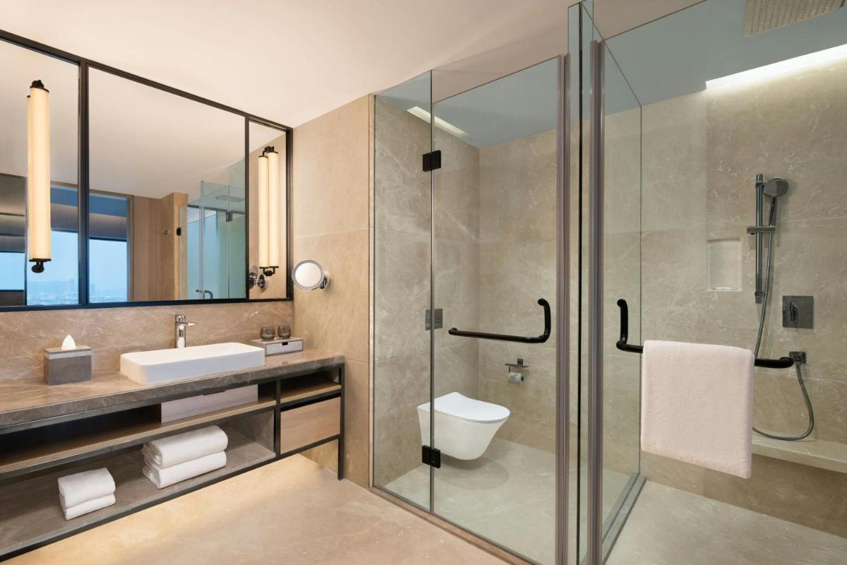 a bathroom with a glass shower and a sink at Le Meridien Ahmedabad in Ahmedabad