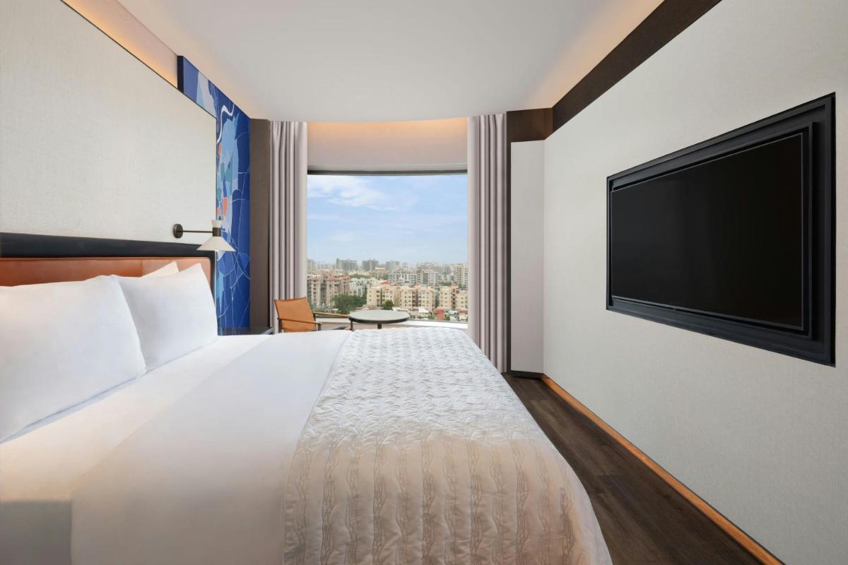 a hotel room with a bed and a flat screen tv at Le Meridien Ahmedabad in Ahmedabad