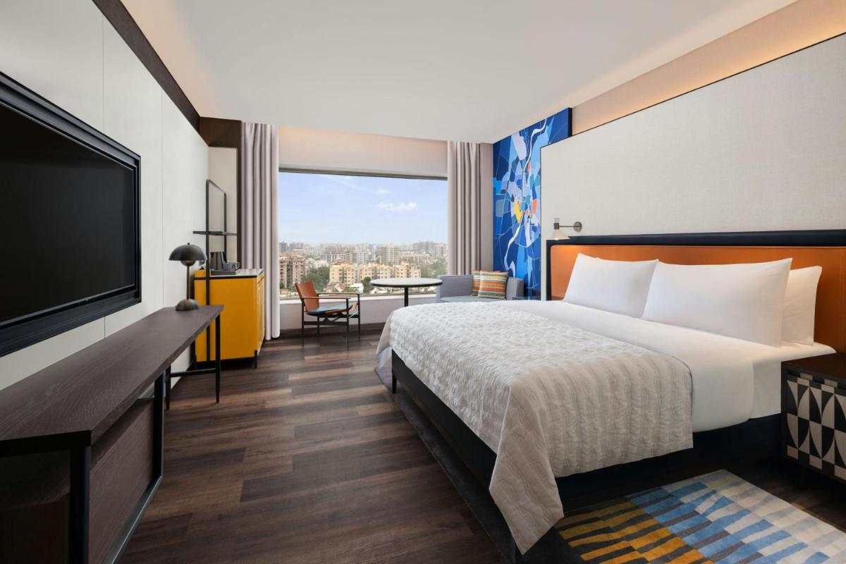 a hotel room with a bed and a flat screen tv at Le Meridien Ahmedabad in Ahmedabad