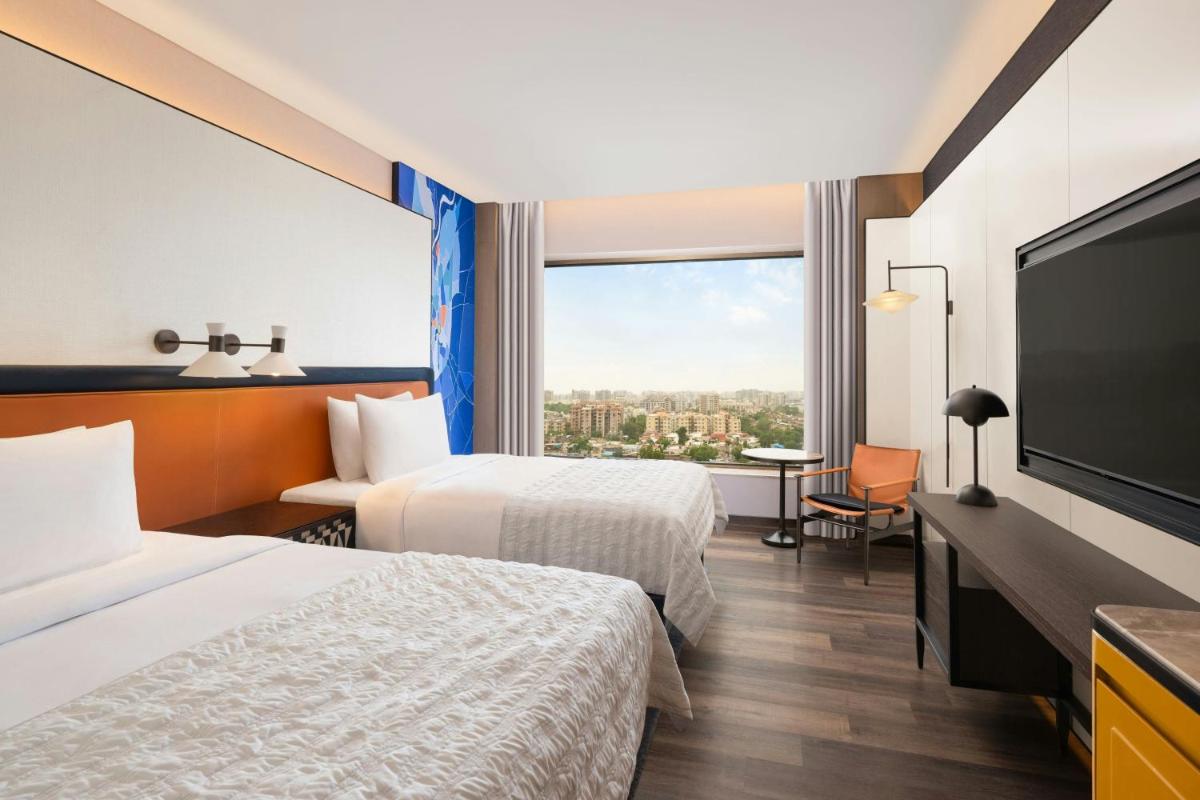 a hotel room with two beds and a flat screen tv at Le Meridien Ahmedabad in Ahmedabad