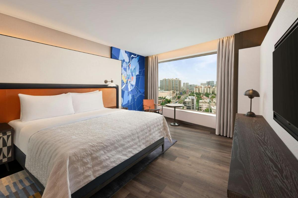 a hotel room with a bed and a large window at Le Meridien Ahmedabad in Ahmedabad