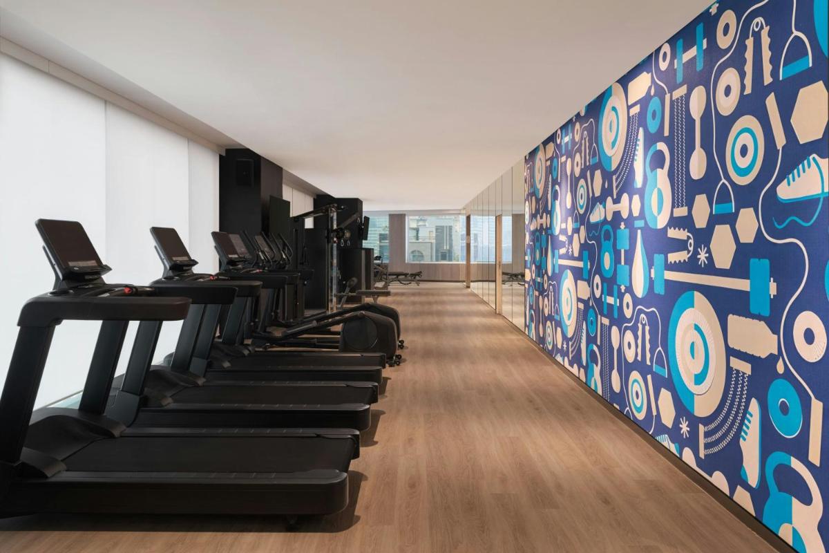 a row of treadmills in a gym with a blue wall at Le Meridien Ahmedabad in Ahmedabad