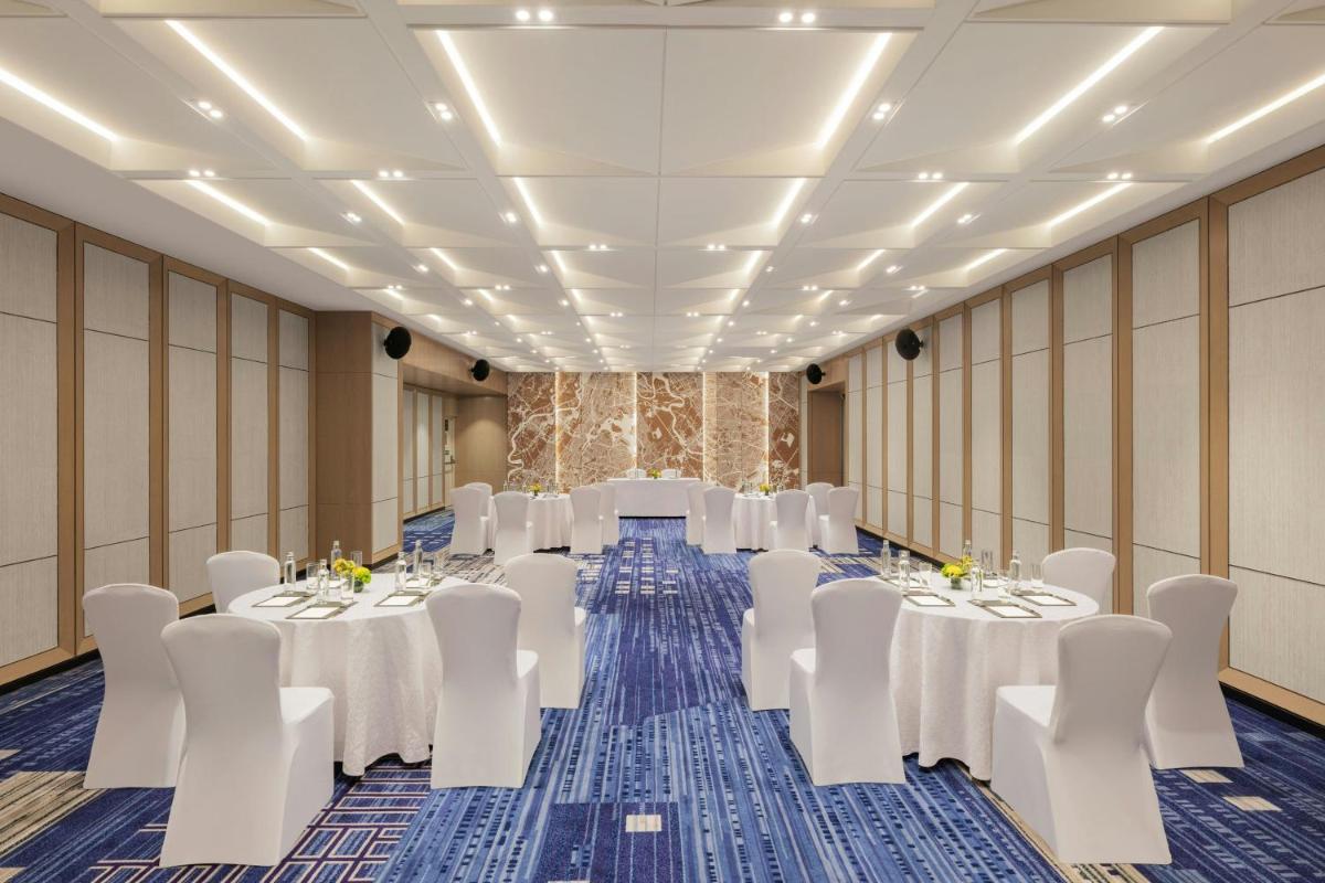 a conference room with white tables and white chairs at Le Meridien Ahmedabad in Ahmedabad
