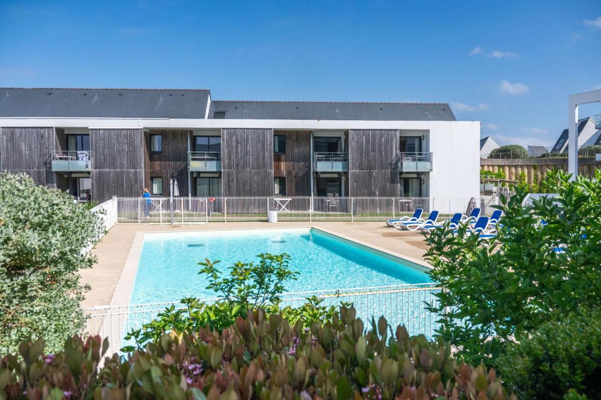 une piscine devant un immeuble dans l'établissement Résidence Odalys Fleur de Sel, à Guidel-Plage