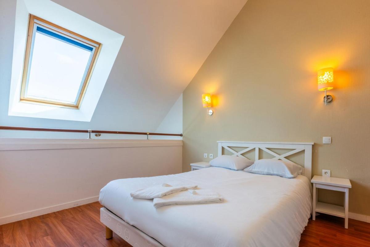 une chambre avec un lit blanc avec des serviettes dessus dans l'établissement Résidence Odalys Fleur de Sel, à Guidel-Plage 56 autres photos