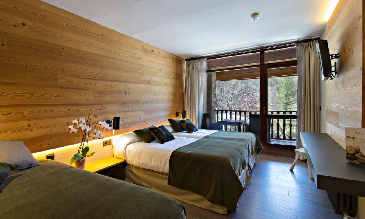 Dos camas en una habitación con paredes de madera. en Hotel La Coma, en Setcases
