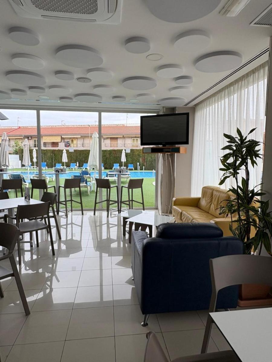 Un restaurante con mesas y sillas y un televisor de pantalla plana. en Hotel Lodomar Spa & Talasoterapia, en San Pedro del Pinatar