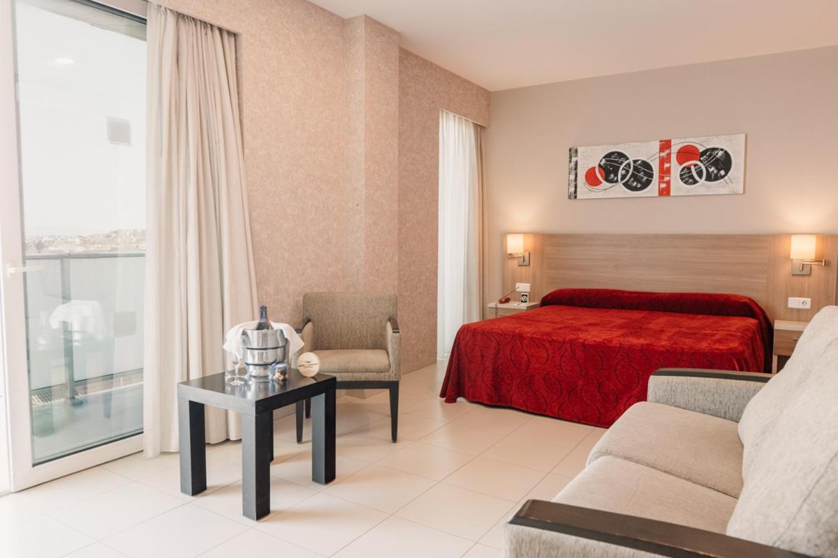 Una habitación de hotel con una cama roja y una silla. en Hotel Lodomar Spa & Talasoterapia, en San Pedro del Pinatar