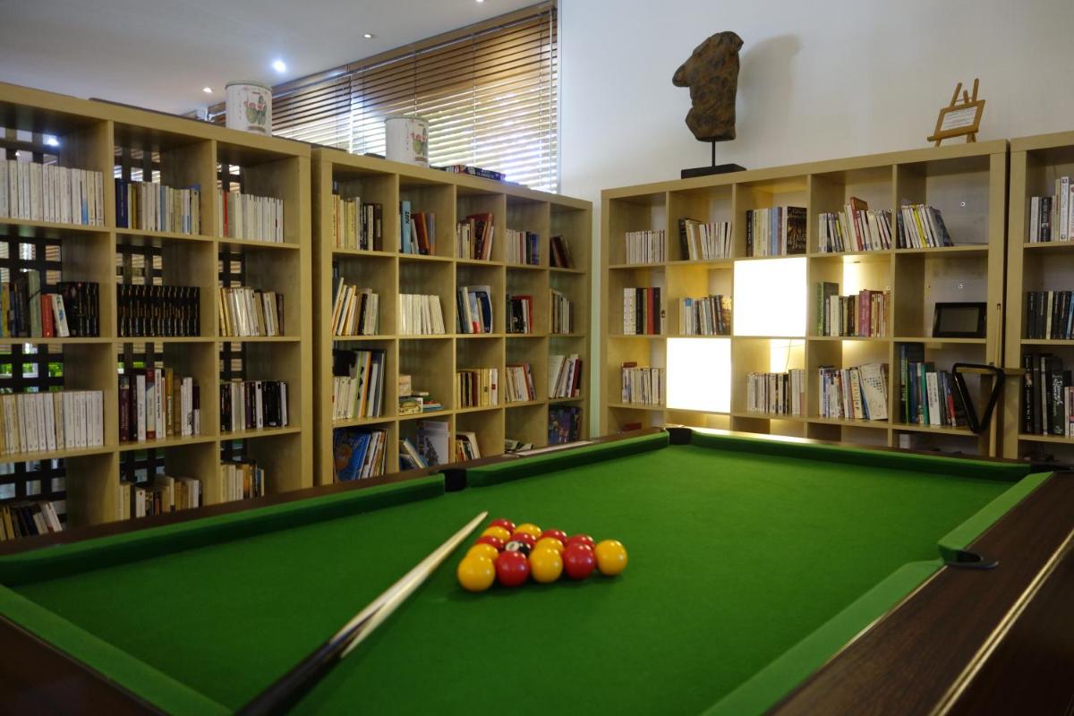 une bibliothèque avec une table de billard verte et des livres dans l'établissement Hôtel La Ségalière Spa Bar, à Cajarc