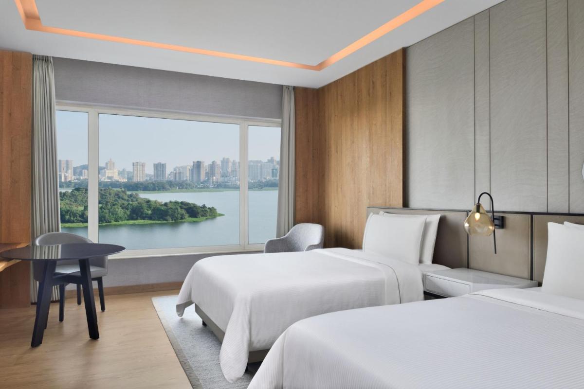 a hotel room with two beds and a large window at The Westin Mumbai Powai Lake in Mumbai