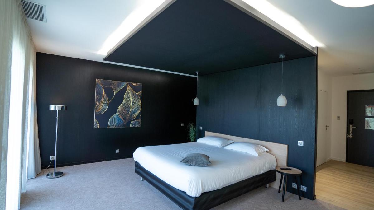 une chambre avec un grand lit avec un mur noir dans l'établissement Les Villas du Parc de la Chabotterie, à Saint-Sulpice-le-Verdon 69 autres photos