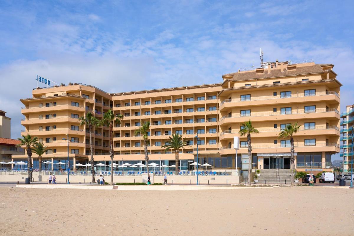 un hotel en la playa con palmeras delante en Hotel & Spa Peñiscola Palace, en Peñíscola