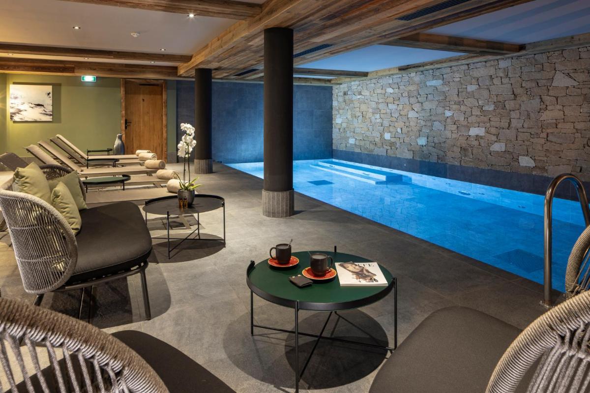 une piscine dans une pièce avec des chaises et des tables et une table dans l'établissement Hotel MONT-BLANC VAL D'ISERE, à Val dʼIsère