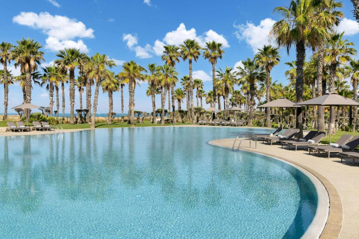 uma piscina com palmeiras e espreguiçadeiras em The Westin Salgados Beach Resort, Algarve em Albufeira