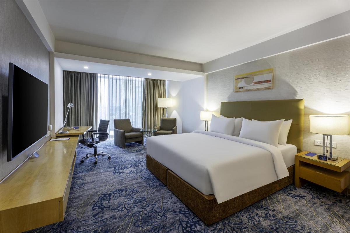 a hotel room with a large bed and a television at Radisson Blu Hotel Pune Kharadi in Pune