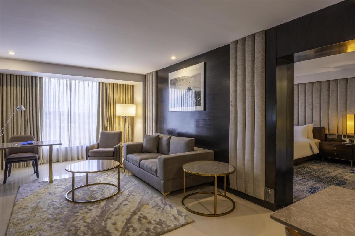a hotel room with a couch and tables and a bed at Radisson Blu Hotel Pune Kharadi in Pune