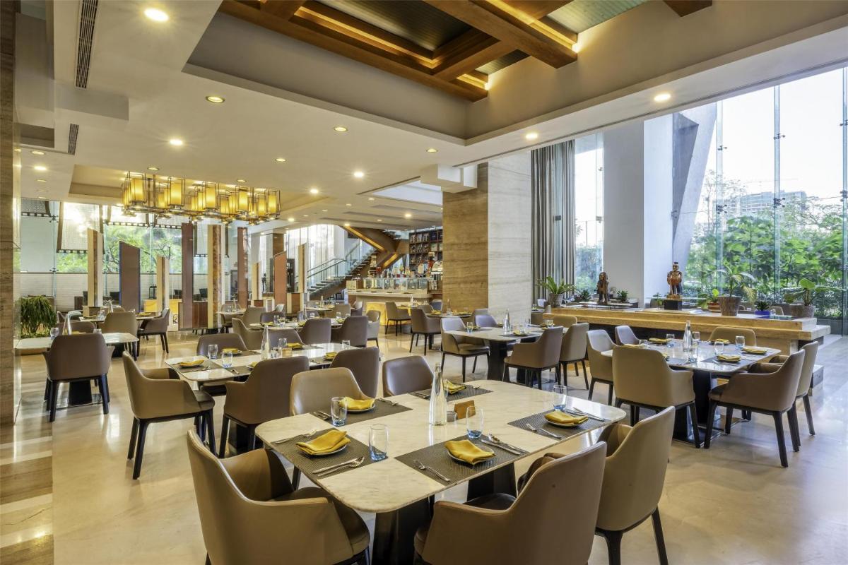 a restaurant with tables and chairs and a bar at Radisson Blu Hotel Pune Kharadi in Pune