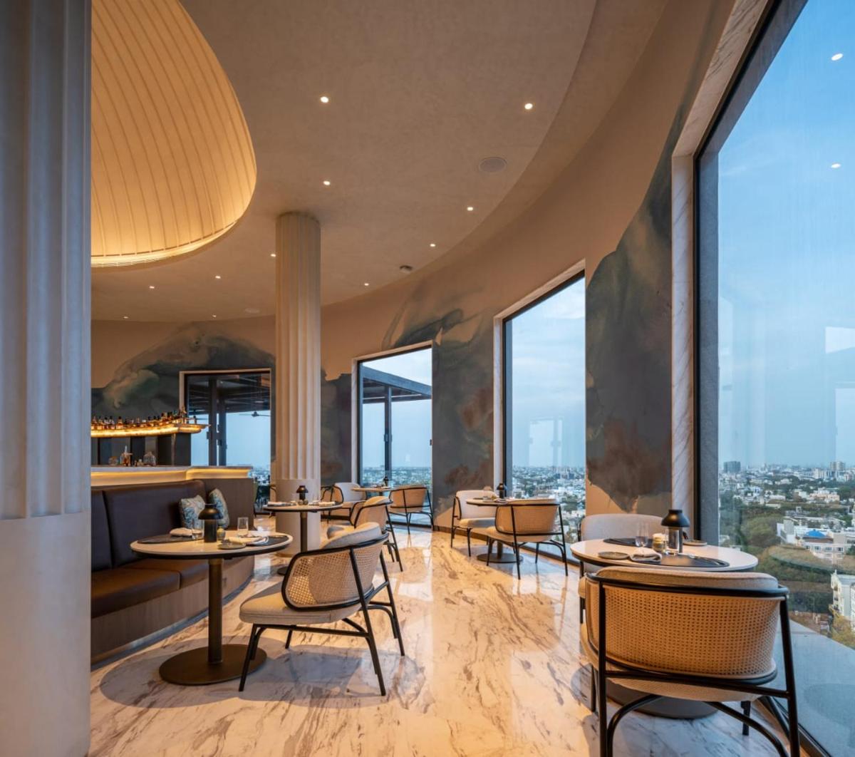a restaurant with tables and chairs and large windows at The Residency Towers in Chennai