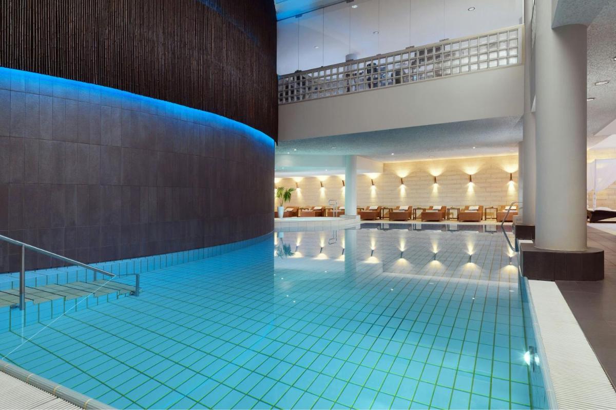 ein großer Pool mit blauen Fliesen in einem Gebäude in der Unterkunft Le Méridien Stuttgart in Stuttgart
