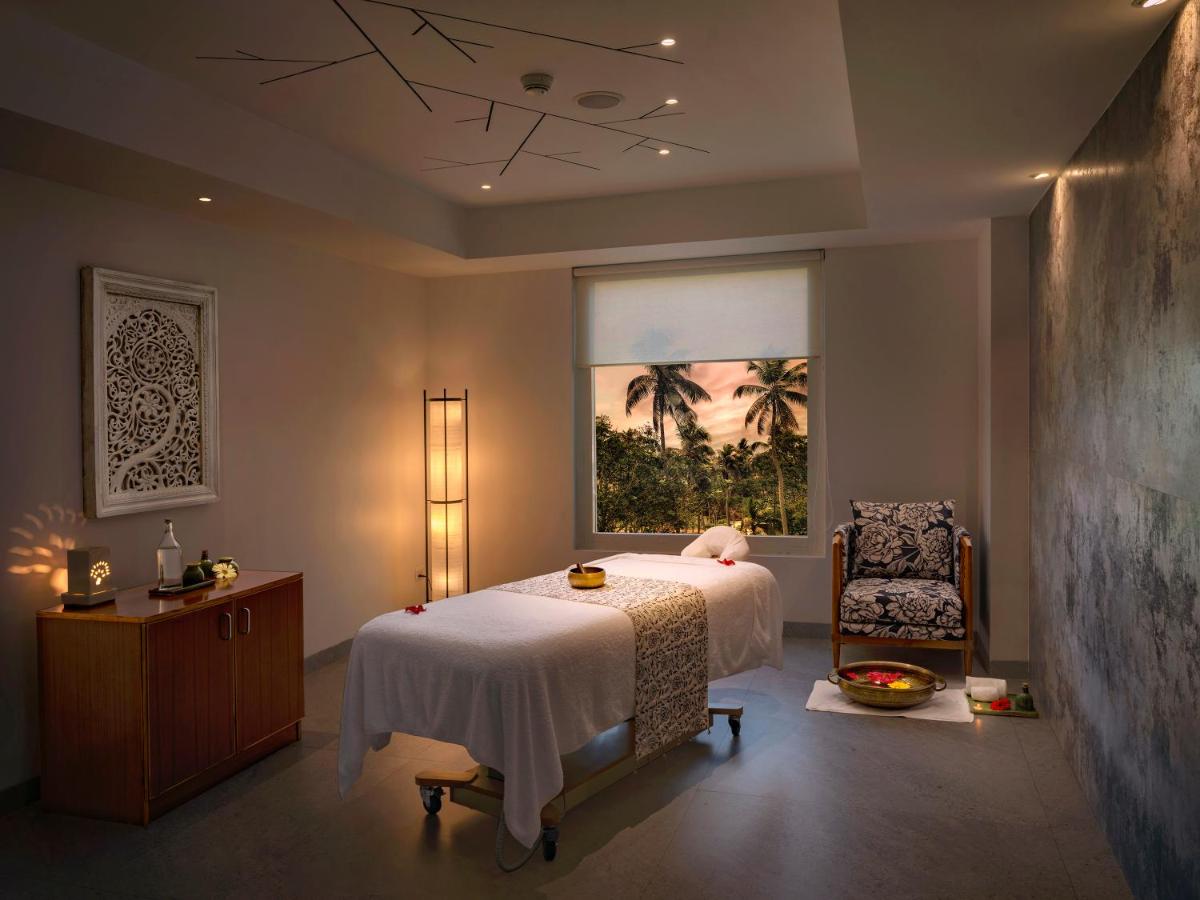 a bedroom with a bed and a chair and a window at O by Tamara, Trivandrum in Trivandrum