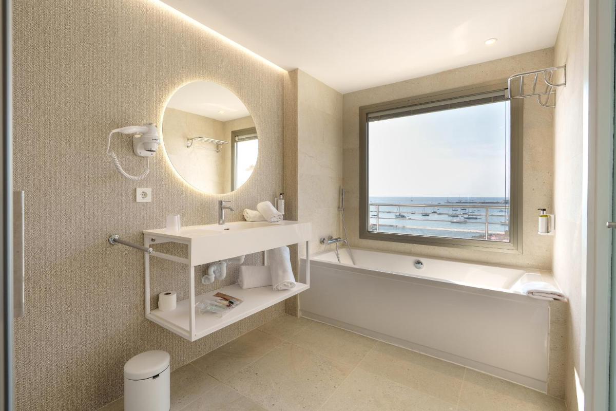 Un baño con bañera, lavabo y espejo. en Bellamar Hotel Beach & Spa, en San Antonio