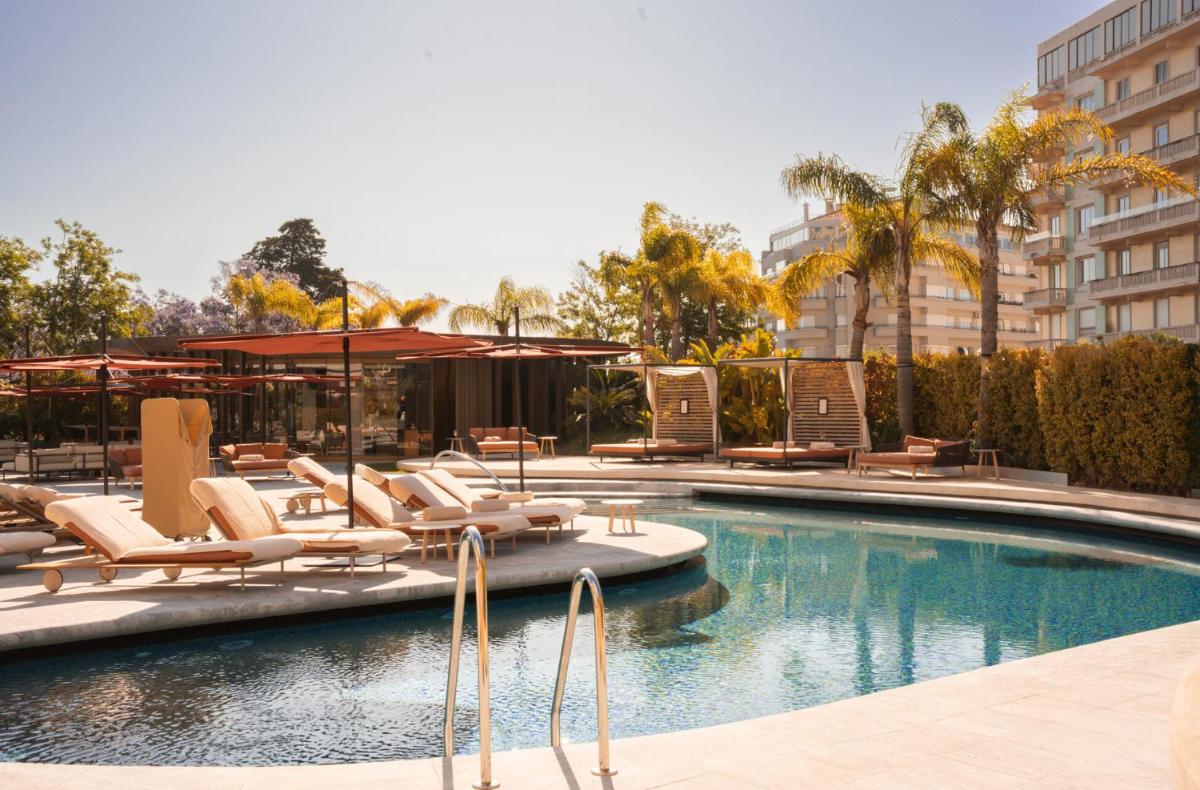 uma piscina com espreguiçadeiras e guarda-sóis em Four Seasons Hotel Ritz Lisbon em Lisboa