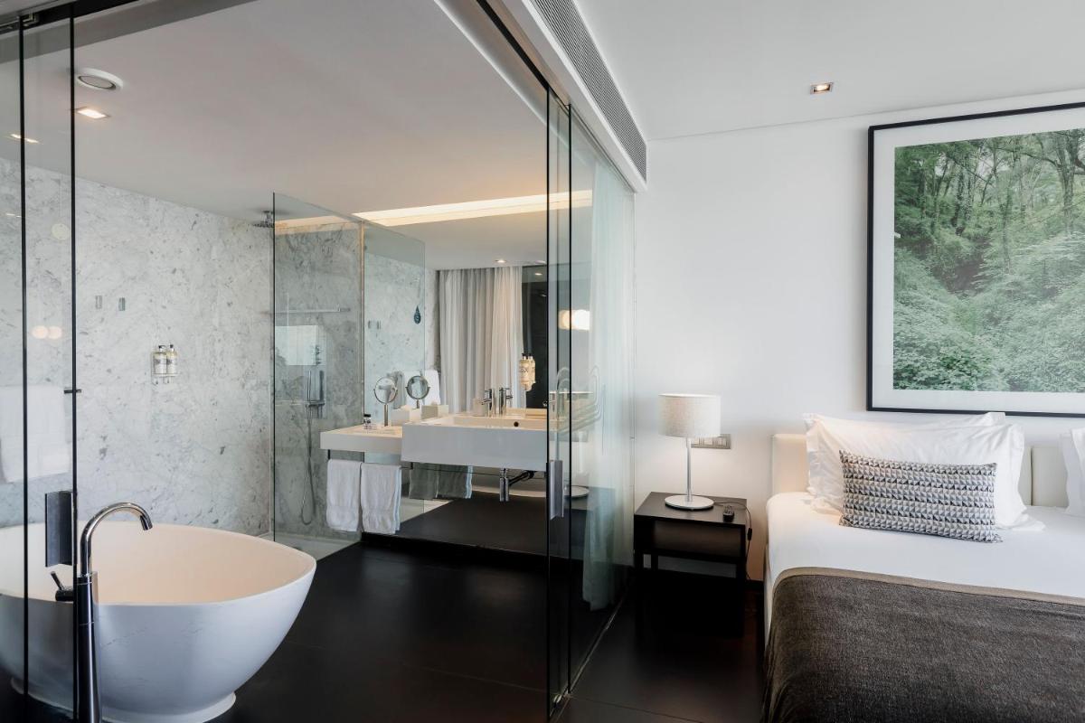 uma casa de banho com uma banheira, uma cama e um chuveiro em Troia Design Hotel em Tróia