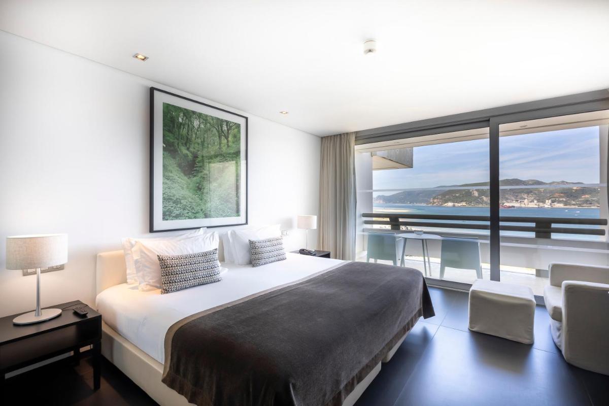 um quarto com uma cama grande e uma janela grande em Troia Design Hotel em Tróia