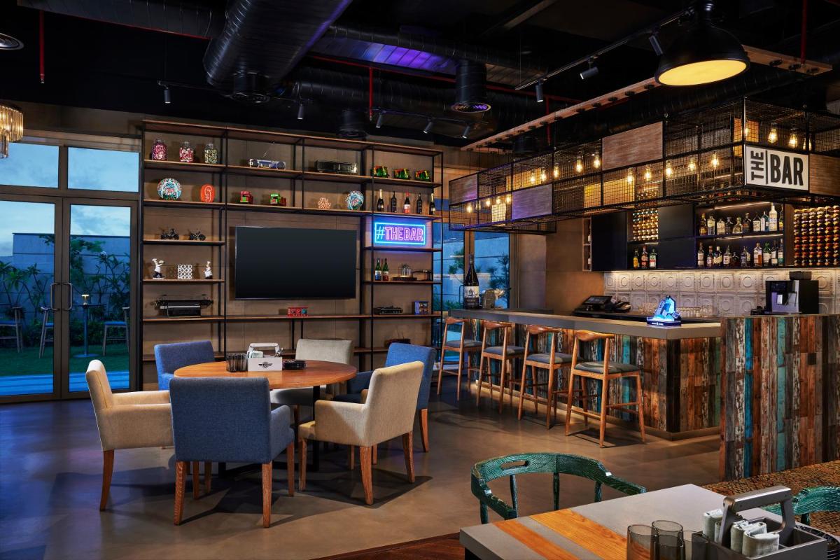 a restaurant with a bar with tables and chairs at Hyatt Place Jaipur Malviya Nagar in Jaipur a restaurant with a bar with tables and chairs at Hyatt Place Jaipur Malviya Nagar in Jaipur