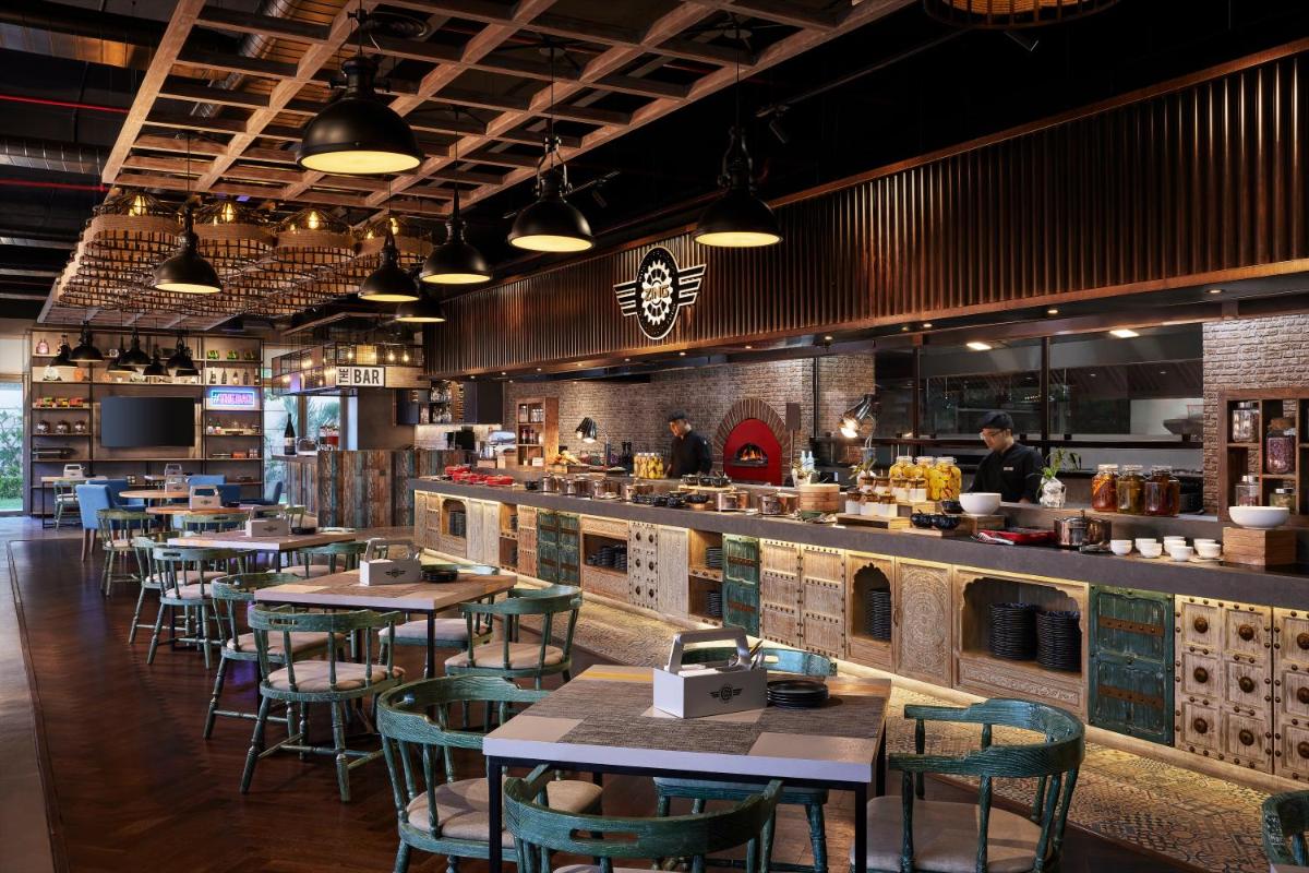 a restaurant with tables and chairs and a counter at Hyatt Place Jaipur Malviya Nagar in Jaipur a restaurant with tables and chairs and a counter at Hyatt Place Jaipur Malviya Nagar in Jaipur