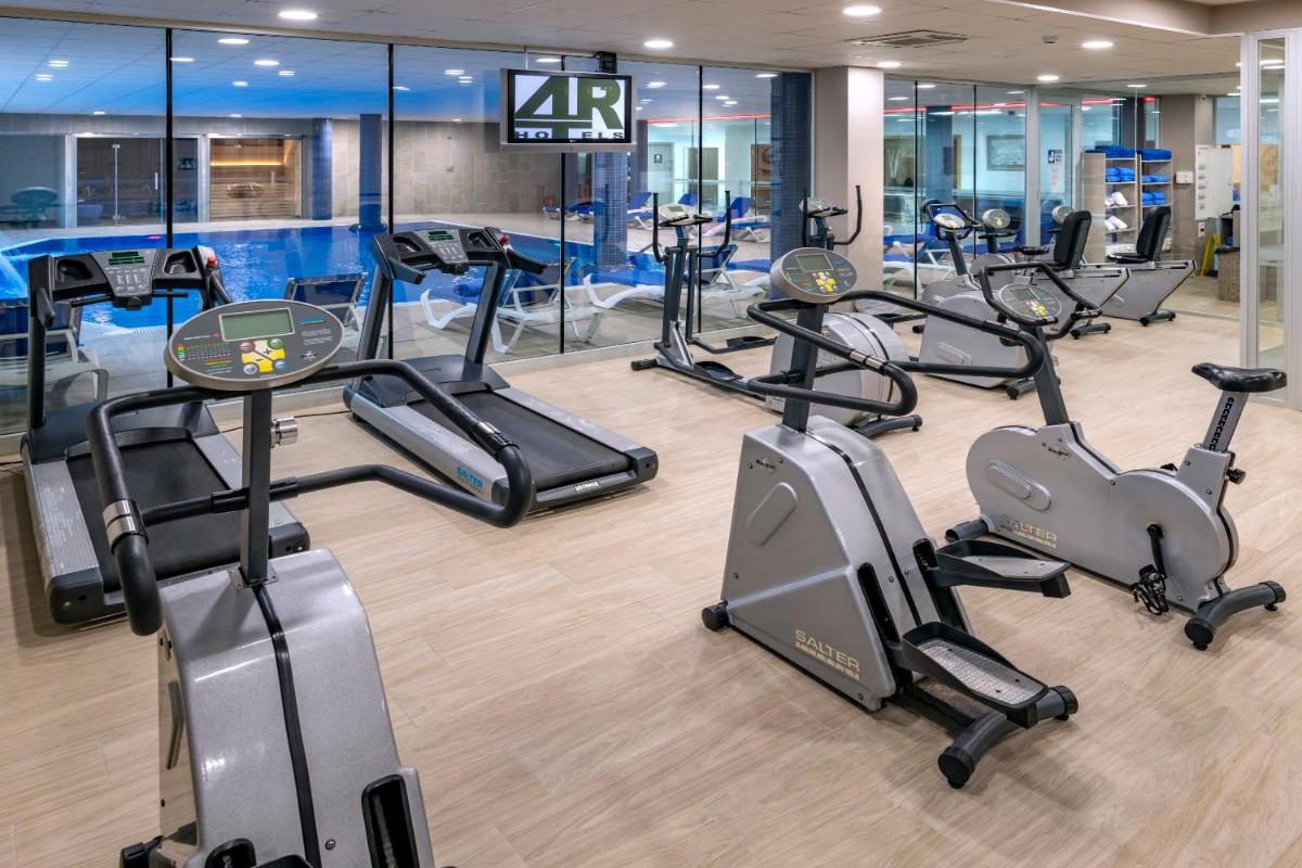 un gimnasio con varias cintas de correr y máquinas elípticas en 4R Gran Regina, en Salou