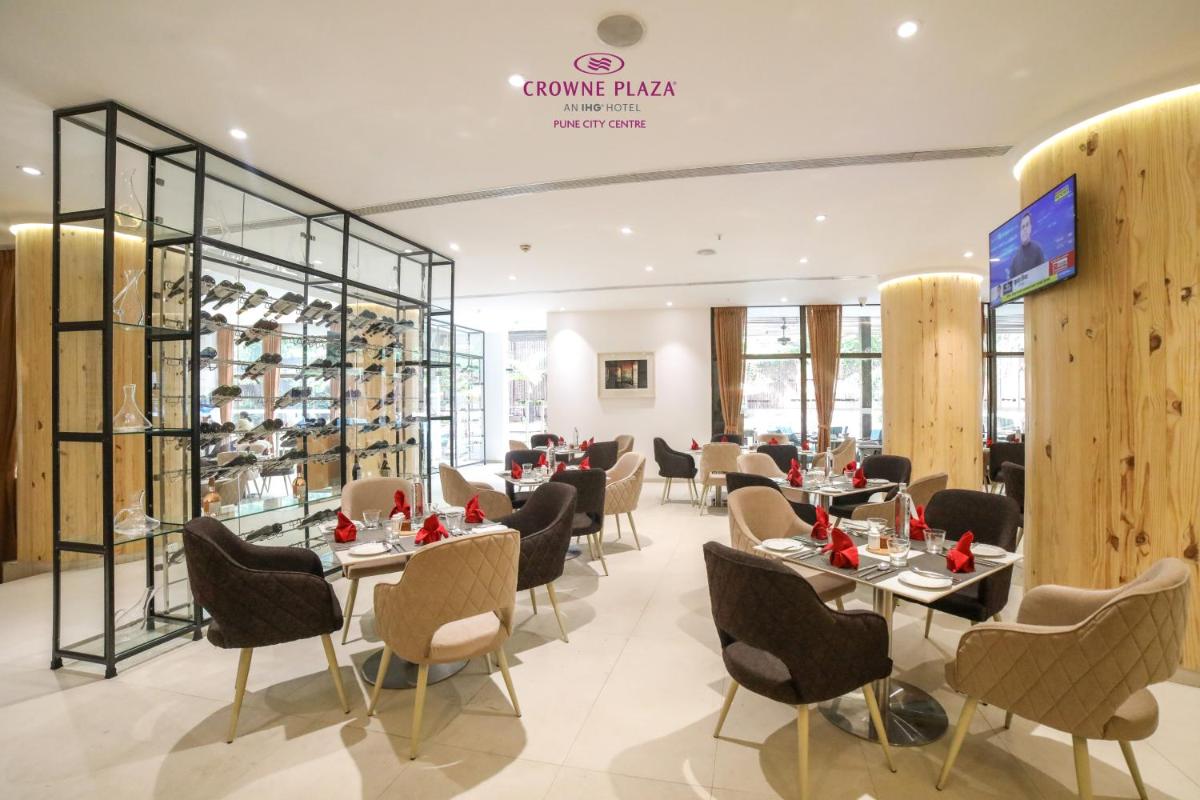 a restaurant with tables and chairs and a wine cellar at Crowne Plaza Pune City Centre by IHG in Pune
