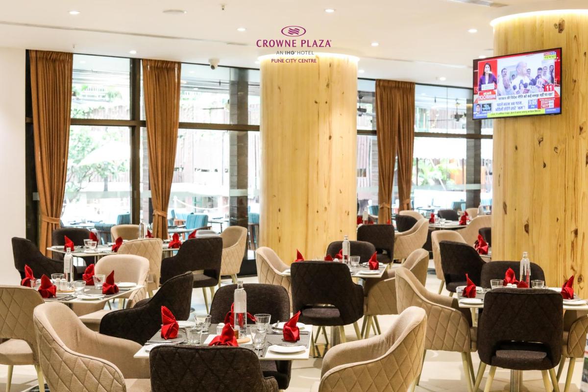 a restaurant with tables and chairs with red bows at Crowne Plaza Pune City Centre by IHG in Pune